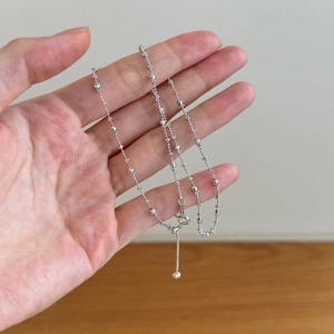 Exquise chaîne perlée en argent sterling S925 tenue à la main sur un fond sobre et simple