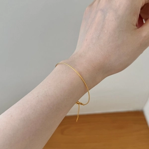 Detail of adjustable gold snake bone chain bracelet with delicate sliding bead closure