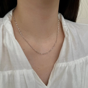 Detail of delicate S925 sterling silver heart-shaped chain links on model neck
