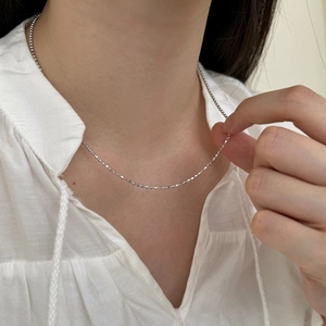 Primer plano de un collar de cadena de bolas minimalista de plata S925 en una modelo
