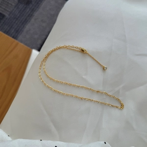 Detailed close-up of golden S925 heart-link chain necklace with a sparkling solitaire pendant