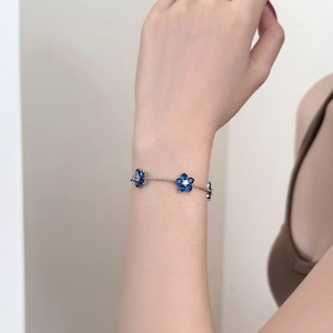 S925 sterling silver bracelet with blue floral charms on a woman's wrist