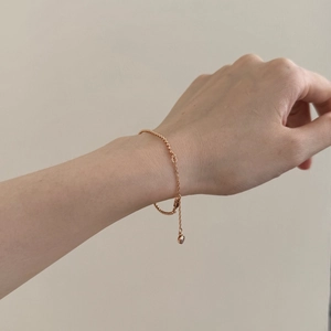 Primer plano de una delicada pulsera de cadena de oro rosa con una pequeña piedra de circón