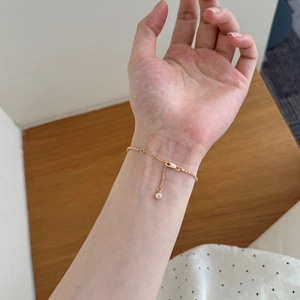Primer plano detallado de la pulsera de cuentas en oro rosa con colgante de circón redondo