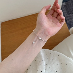 Detalle de una pulsera de plata S925 con cuentas y un dije de circón en la muñeca