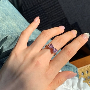 Dettaglio dell'anello in argento S925 con pietre a cuore rosa e design a fiocco al dito