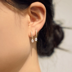 Close-up of elegant gold water drop earrings with zircon pavé setting on a model