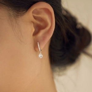 Detail shot of a s925 silver pear-shaped water drop earring worn on a model ear