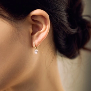 Detail of gold oval crystal earring featuring a micro-paved hoop and large drop stone