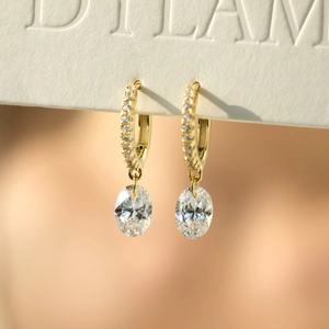 Macro view of gold-plated silver earrings with pavé-set hoops and oval zircon pendants