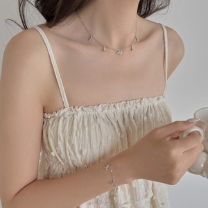 Détail du set collier et bracelet papillon en argent S925 sur mannequin, lumière douce
