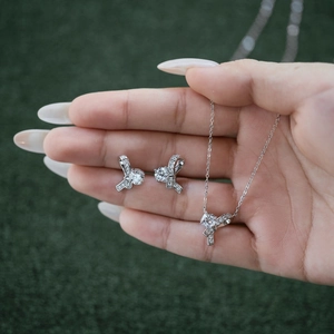 Macro shot of silver bow jewelry set with round zircon stones held in hand
