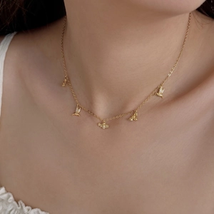Gros plan d'un collier en argent S925 doré avec breloques oiseaux et abeilles brillants
