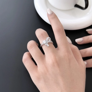 Close-up of S925 sterling silver bow ring with sparkling zircons worn by a model