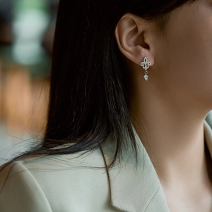 Detail of S925 silver fleur-de-lis earring with full diamond pave and teardrop pendant