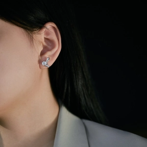 Detailed view of silver bow-shaped stud earrings with zircons worn on a model