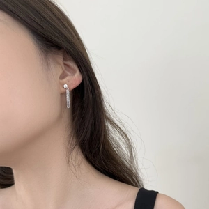 Detail view of silver tassel earrings with round stud on model's ear for daily wear