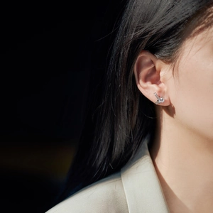Detailed view of silver bow-shaped stud earrings with sparkling cubic zirconia on model