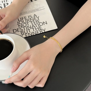 Elegant gold minimalist curb chain bracelet with butterfly charm on a model hand