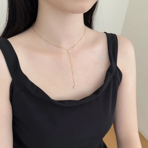 Close-up of a minimalist golden Y-shaped necklace with dual zircon pendants on a model