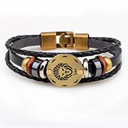 Détail d'un bracelet Léo multicouche en cuir noir avec breloques en bronze et signe astro