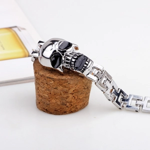 Silver punk skull bracelet in stainless steel with black enamel details on cork stand