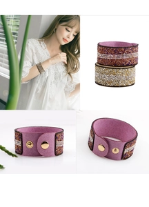Makro-Detail von Mikrofaser-Breitarmband mit bunten Strasssteinen und Gold-Druckknöpfen