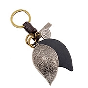 Dettaglio del ciondolo a foglia di bronzo e cuoio nero su un portachiavi intrecciato