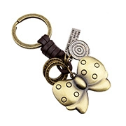 Dettaglio di portachiavi vintage in bronzo con pelle, ingranaggio e fiocco a pois