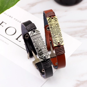 Vintage Lederarmband-Set mit Kreuz- und Blattanhängern auf Marmoroberfläche