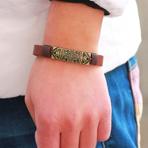 Vintage braunes Lederarmband mit Bronze-Blatt-Plakette am Handgelenk eines Mannes