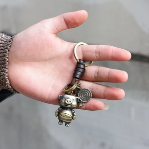 Porte-clés cochon vintage en alliage de bronze et cuir tenu en main pour démonstration