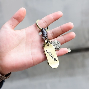 Retro bronze skateboard keychain with LOVE engraving and dark brown leather cord loop
