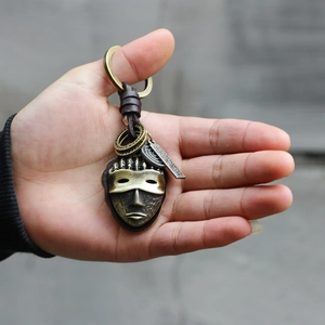 Vintage tribal mask car keychain with woven brown leather cord and antique bronze finish