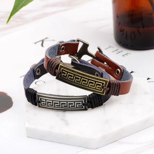 Set of two vintage leather bracelets featuring Greek fret pattern on marble display