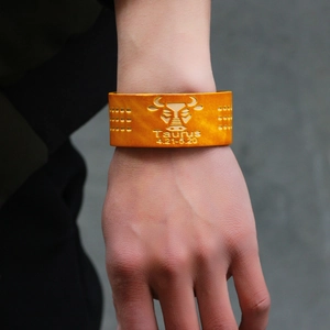Gelbes Lederarmband Sternzeichen Stier mit geprägtem Stiersymbol und Datum am Handgelenk