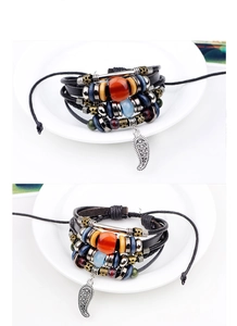 Detail of multi-layer woven leather bracelet with ethnic beads and vintage leaf pendant