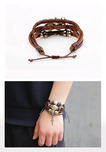 Detail eines mehrlagigen braunen Lederarmbands mit Bronzekreuz und Perlenstruktur