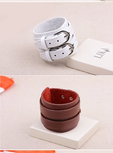 Detail of wide multi-layer leather bracelets in white and brown with double metal buckles