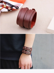 Macro view of wide brown leather cuff bracelet with dual metal buckles and red lining