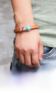 Détail du bracelet en cuir marron avec pierre turquoise et lettrage MIO en métal