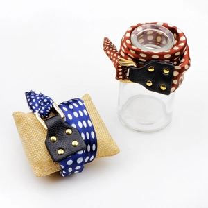 Polka dot silk scarf bracelet with leather connector and gold buckle shown on prop