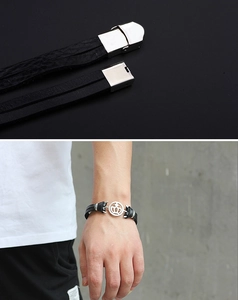 Detail of men's black leather crown bracelet showing woven texture and silver steel clasp