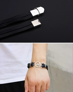 Detail of black leather anchor bracelet with silver clasp and letter M metal logo