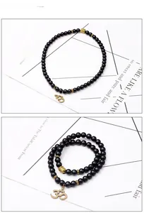 Détail du bracelet en perles noires mates avec pendentif Om doré et tête de Bouddha