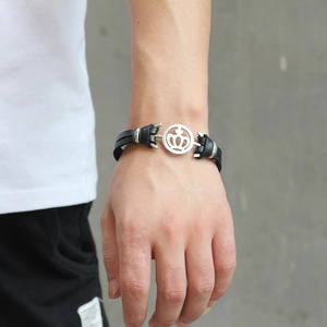 Men's black leather bracelet with silver crown charm on a hand, casual punk style