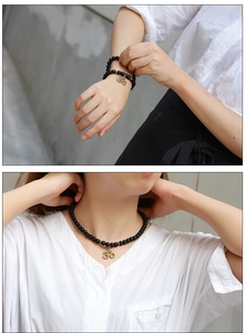 Gros plan d'un bracelet en perles noires mates avec un pendentif symbole Om en bronze