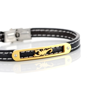 Close-up of leather bracelet with white stitching and golden scorpion charm detail