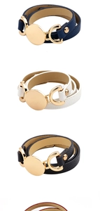 Detail of three leather wrap bracelets in navy, ivory, and black with gold metal discs