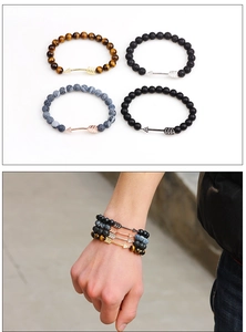 Détails de bracelets en perles superposés avec pierres et breloques flèche